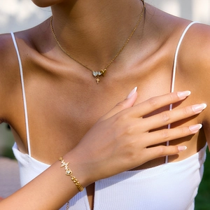 Model wearing 18K gold stainless steel heart and cross pendant necklace and bracelet set