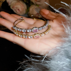 Detail of gold and silver bracelets with pink oval zircon and white diamond accents
