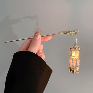 Macro detail of glowing lantern hair pin with pearls and golden metallic tassels