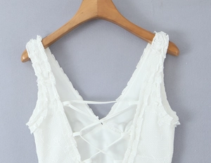 Detail of white lace dress featuring a criss-cross lace-up back design and sheer mesh fabric