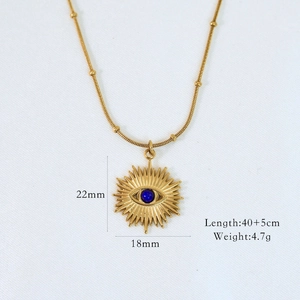 Detail of 14K gold starburst pendant necklace with blue eye bead and textured chain