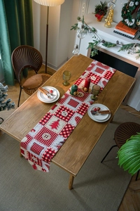 Detail view of festive Christmas table runner with red plaid and tree patterns on wood