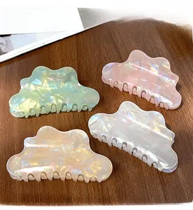Close-up of four cloud-shaped acetate hair claws in iridescent green, pink, and white
