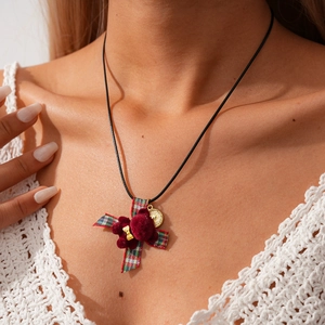 Detail of flocked bear pendant with plaid bow on a black cord necklace for women