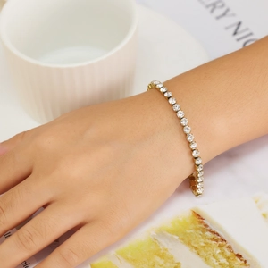 Detail shot of a golden tennis bracelet with sparkling clear zircon stones on a model wrist