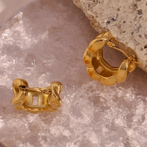 Macro detail of 18K gold plated chunky hoop earrings with wavy texture on rock background
