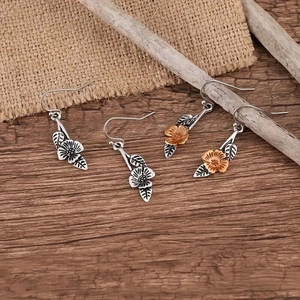 Detailed macro view of vintage silver floral drop earrings on a rustic wood background