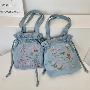 Macro shot of colorful cherry and tulip embroidery patterns on blue denim tote bags