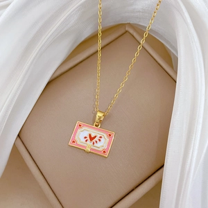 Detailed macro of gold heart-book pendant with pink enamel and red heart motif