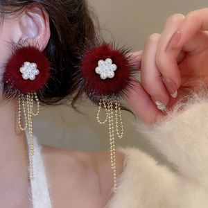Detail of red faux fur flower earrings with pearl center and golden tassel chains