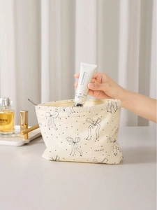 Minimalist beige makeup bag with black bow and dots pattern, showing spacious capacity