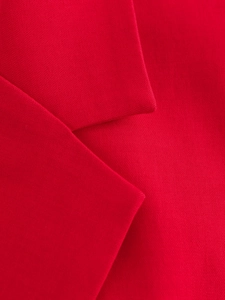 Détail de la texture du tissu rouge et des coutures précises du col de gilet