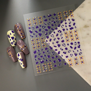 Detail view of purple leopard pattern nail stickers and diamond cross line art on model nails