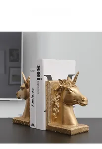 Nahaufnahme goldener Einhorn-Buchstützen mit mattem Finish und strukturierter Holzbasis