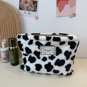 Plush cow print coin purse with Time to Party label on a minimalist aesthetic vanity