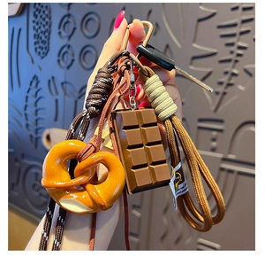 Detail of creative pretzel and chocolate charms with colorful woven cords on a keychain