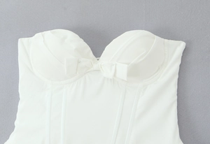 Detailed close-up of a white corset top featuring a sweet bow and structured boning seams