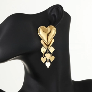 Detailed view of long 18k gold plated heart tassel earrings on a display model