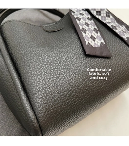 Detail of black lychee grain leather bucket bag with geometric silk scarf handle