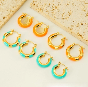 Detail of vintage gold hoop earrings with orange and turquoise enamel coating on stone