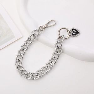 Detailed view of silver rhinestone chain with black heart bow pendant on white base