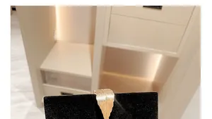 Detailed close-up of a golden feather brooch with textured metal on a black display stand