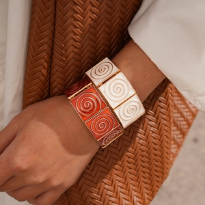 Macro view of stacked enamel square link bracelets with golden spiral textures