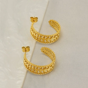 Golden C-shaped hollow earrings with leaf-like textures on white marble background