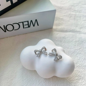 Detail of silver bow earrings with zircon pavé on a white decorative cloud stand