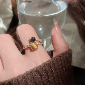 Detail of tiger eye stone ring with gold plating and zircons on a model's hand