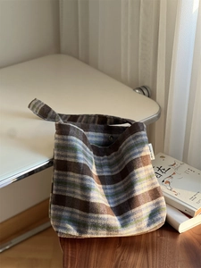 Vue détaillée du sac cabas rétro en laine à carreaux avec étiquette et lumière chaude