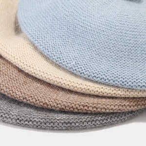 Detail of stacked knit berets in blue, beige, brown and grey showing soft fuzzy texture