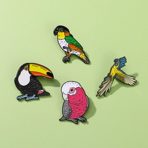 Set of four tropical bird enamel pins including toucan and parrot on a green background