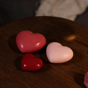 Three sizes of heart-shaped resin molds in red and pink on a dark wood surface