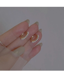 Detailed close-up of a gold pearl hoop earring held by hand featuring small white pearls