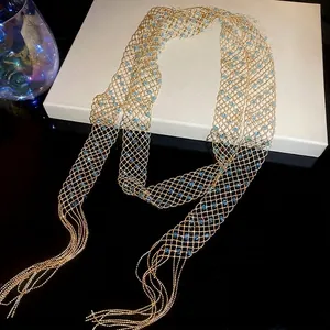 Gold beaded mesh cape necklace with light blue crystals and long tassels on jewelry box