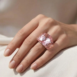 Close-up of oversized pink faceted crystal ring with 18k gold plating on silk fabric
