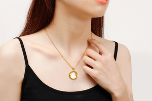 Close-up of golden O-chain necklace with a round pineapple pendant on model's neckline