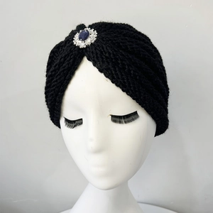 Detail of black knitted turban hat featuring vintage blue gemstone and silver rhinestones