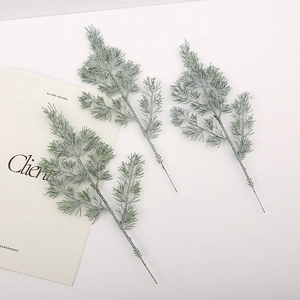 Detailed close-up of three artificial frosted pine branches with grey-green leaves
