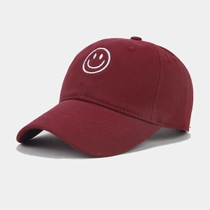 Detail of white embroidered smiley face on burgundy cotton twill baseball cap