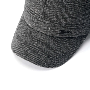 Dettaglio ravvicinato della trama a quadri grigi e logo in metallo del cappello