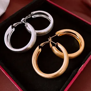 Minimalist brushed metal hoop earrings in gold and silver finish on a black velvet base
