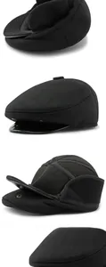 Detail view of black wool newsboy cap featuring leather brim and ear flaps with snap button