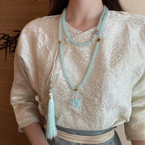 Detail of a Neo-Chinese style long necklace with light blue beads and a silk tassel