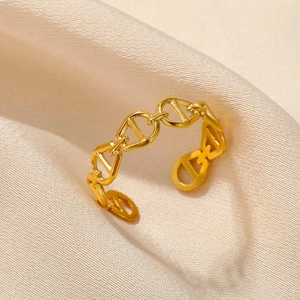 Adjustable gold stainless steel ring with anchor chain design on white satin fabric