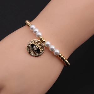 Détail d'un bracelet œil maléfique avec perles d'imitation blanches et pendentif doré