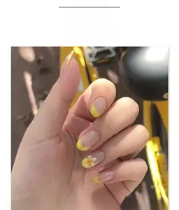 Short round press-on nails with yellow French tips and white flower accents on fingers