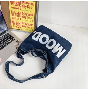 Deep blue denim shoulder bag with bold MOOD letter print in a trendy lifestyle setting