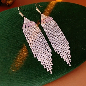 Detail of silver long tassel earrings with purple and pink gemstones on velvet